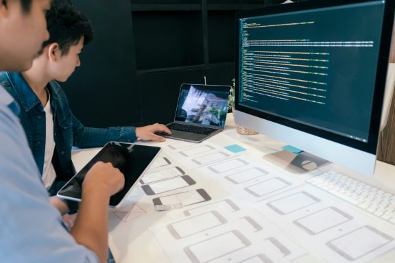 Zwei Personen arbeiten an einem Webdesign-Projekt mit Tablets und Laptop.