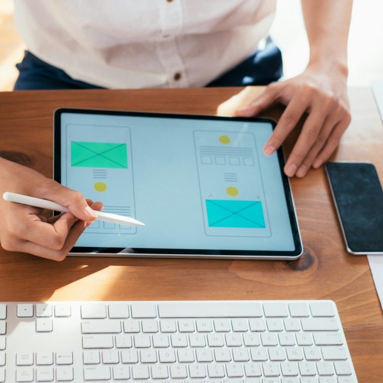 Person arbeitet an einem Tablet, umgeben von Notizen und einem Smartphone.