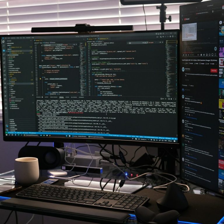 Ein Schreibtisch mit zwei Monitoren, einer zeigt Code, der andere Nachrichten und Apps.